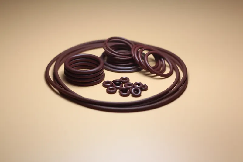 Dark red EPDM sealing rings of varying diameters arranged on a tan surface