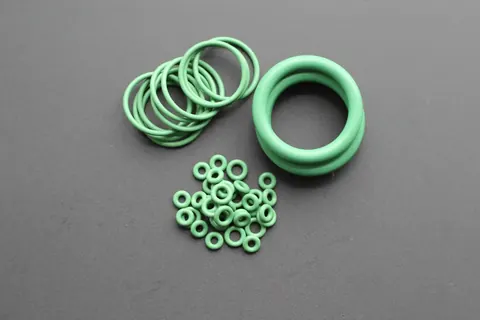 Green perfluoroelastomer O-rings in several diameters grouped on a grey background
