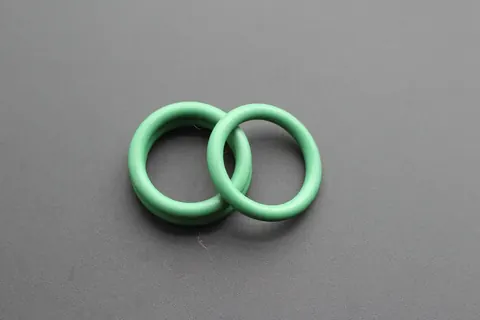 Two large green FFKM O-rings resting side by side on a grey surface