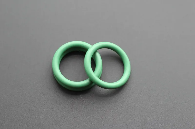 Two green perfluoroelastomer O-rings resting on a grey background
