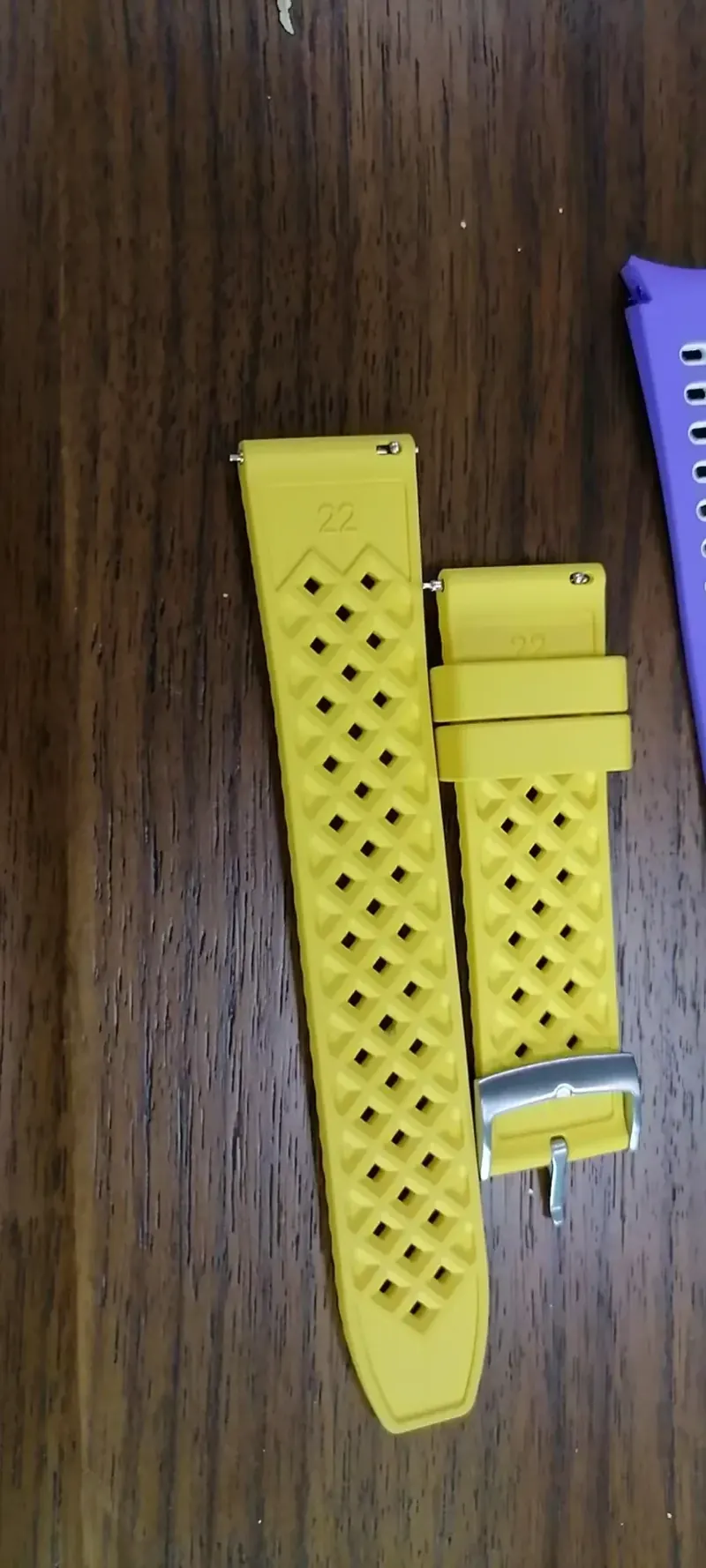 Yellow moulded rubber strap with a row of ventilation holes resting on a wooden bench