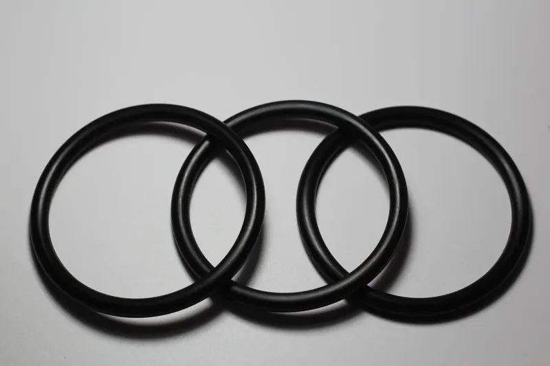 Four black nitrile O-rings of graduated diameter arranged on a light surface