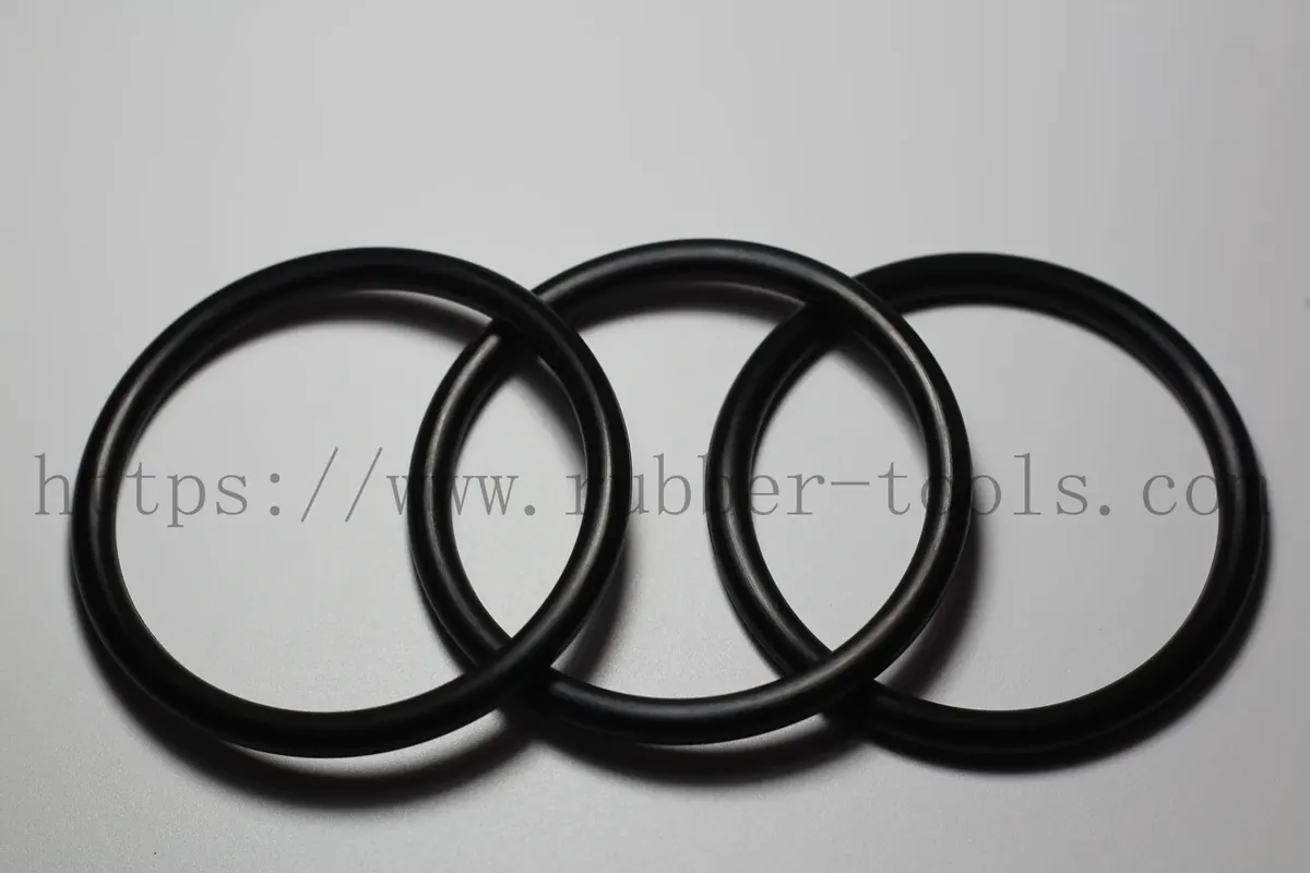 Four black nitrile O-rings of graduated diameter on a light grey surface