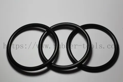 Four black nitrile O-rings of graduated diameter on a light grey surface