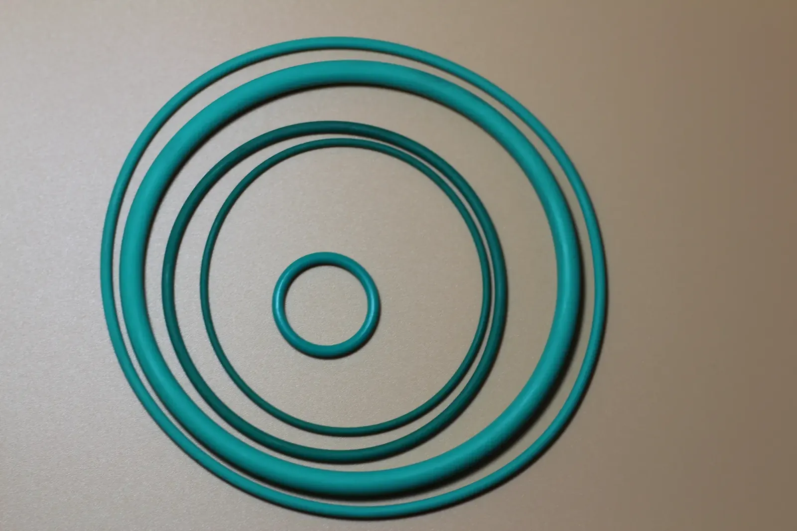 Teal fluoroelastomer O-rings of several diameters laid out on a work surface